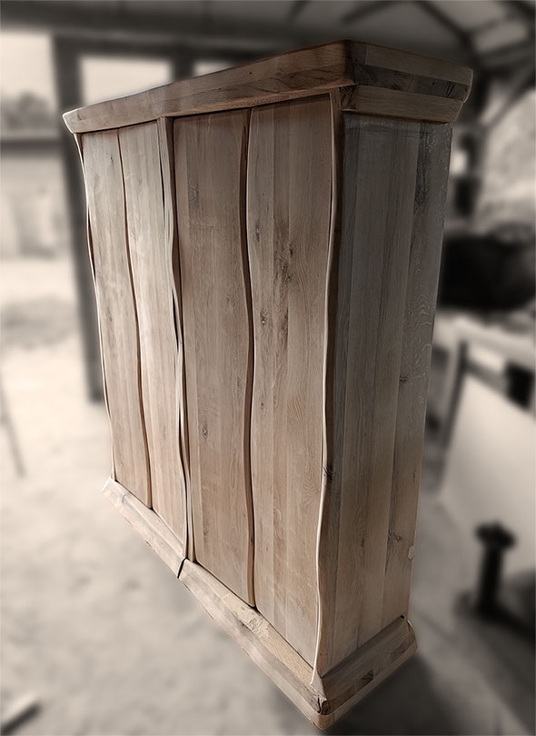 Ručno rađena vinska polica od punog hrastovog drveta sa karakterističnim talasastim ivicama i prirodnom teksturom drveta. Rustičan, a moderan dizajn ormarića za vino visokog kvaliteta, fotografisan u stolarskoj radionici.